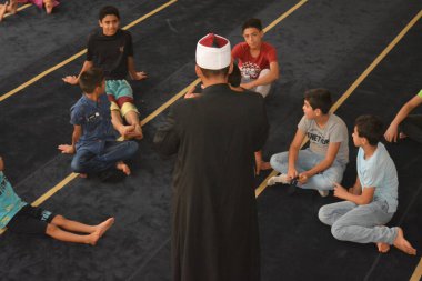 Cairo, Egypt, August 7 2022: A mosque preacher Imam performs a religious Khutbah (sermon) for young Muslim children inside a mosque during the summer Islamic educational program for kids in the mosque