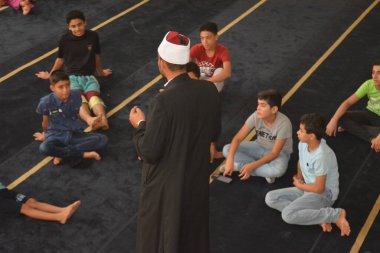 Cairo, Egypt, August 7 2022: A mosque preacher Imam performs a religious Khutbah (sermon) for young Muslim children inside a mosque during the summer Islamic educational program for kids in the mosque