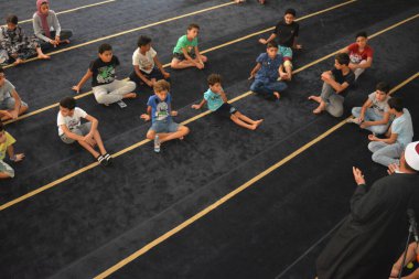 Cairo, Egypt, August 7 2022: A mosque preacher Imam performs a religious Khutbah (sermon) for young Muslim children inside a mosque during the summer Islamic educational program for kids in the mosque