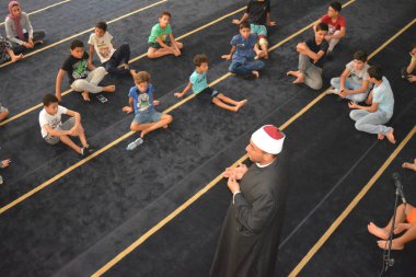 Cairo, Egypt, August 7 2022: A mosque preacher Imam performs a religious Khutbah (sermon) for young Muslim children inside a mosque during the summer Islamic educational program for kids in the mosque