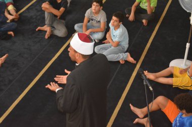 Cairo, Egypt, August 7 2022: A mosque preacher Imam performs a religious Khutbah (sermon) for young Muslim children inside a mosque during the summer Islamic educational program for kids in the mosque