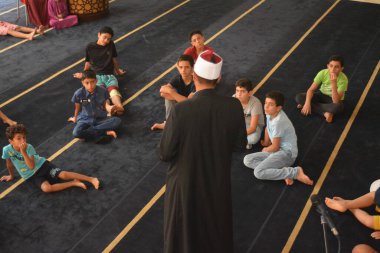 Cairo, Egypt, August 7 2022: A mosque preacher Imam performs a religious Khutbah (sermon) for young Muslim children inside a mosque during the summer Islamic educational program for kids in the mosque