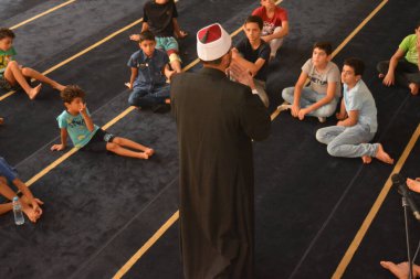 Cairo, Egypt, August 7 2022: A mosque preacher Imam performs a religious Khutbah (sermon) for young Muslim children inside a mosque during the summer Islamic educational program for kids in the mosque