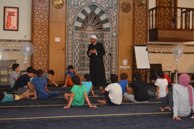 Cairo, Egypt, August 7 2022: A mosque preacher Imam performs a religious Khutbah (sermon) for young Muslim children inside a mosque during the summer Islamic educational program for kids in the mosque