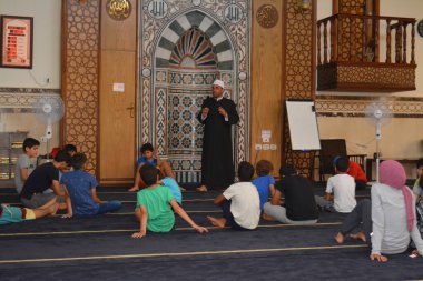 Cairo, Egypt, August 7 2022: A mosque preacher Imam performs a religious Khutbah (sermon) for young Muslim children inside a mosque during the summer Islamic educational program for kids in the mosque