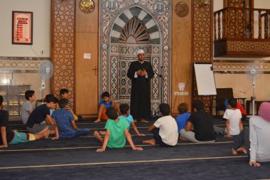Cairo, Egypt, August 7 2022: A mosque preacher Imam performs a religious Khutbah (sermon) for young Muslim children inside a mosque during the summer Islamic educational program for kids in the mosque
