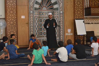 Cairo, Egypt, August 7 2022: A mosque preacher Imam performs a religious Khutbah (sermon) for young Muslim children inside a mosque during the summer Islamic educational program for kids in the mosque