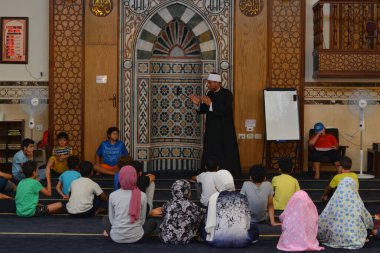 Cairo, Egypt, August 7 2022: A mosque preacher Imam performs a religious Khutbah (sermon) for young Muslim children inside a mosque during the summer Islamic educational program for kids in the mosque