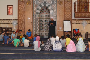 Cairo, Egypt, August 7 2022: A mosque preacher Imam performs a religious Khutbah (sermon) for young Muslim children inside a mosque during the summer Islamic educational program for kids in the mosque