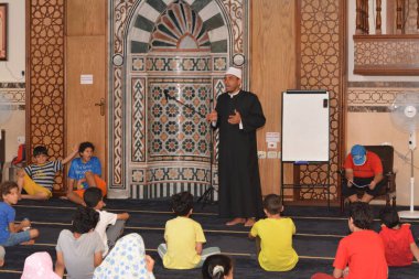 Cairo, Egypt, August 7 2022: A mosque preacher Imam performs a religious Khutbah (sermon) for young Muslim children inside a mosque during the summer Islamic educational program for kids in the mosque