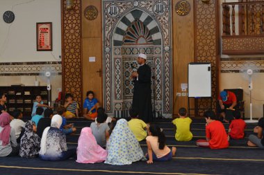 Cairo, Egypt, August 7 2022: A mosque preacher Imam performs a religious Khutbah (sermon) for young Muslim children inside a mosque during the summer Islamic educational program for kids in the mosque