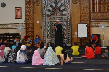 Cairo, Egypt, August 7 2022: A mosque preacher Imam performs a religious Khutbah (sermon) for young Muslim children inside a mosque during the summer Islamic educational program for kids in the mosque
