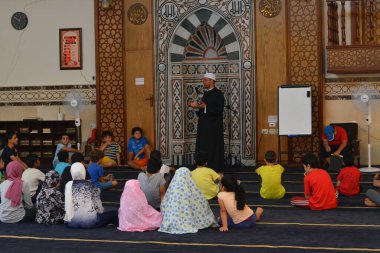 Cairo, Egypt, August 7 2022: A mosque preacher Imam performs a religious Khutbah (sermon) for young Muslim children inside a mosque during the summer Islamic educational program for kids in the mosque