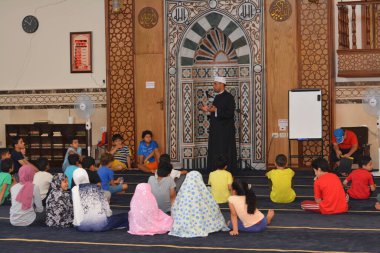 Cairo, Egypt, August 7 2022: A mosque preacher Imam performs a religious Khutbah (sermon) for young Muslim children inside a mosque during the summer Islamic educational program for kids in the mosque