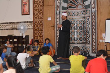 Cairo, Egypt, August 7 2022: A mosque preacher Imam performs a religious Khutbah (sermon) for young Muslim children inside a mosque during the summer Islamic educational program for kids in the mosque