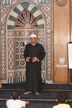 Cairo, Egypt, August 7 2022: A mosque preacher Imam performs a religious Khutbah (sermon) for young Muslim children inside a mosque during the summer Islamic educational program for kids in the mosque