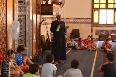 Cairo, Egypt, August 7 2022: A mosque preacher Imam performs a religious Khutbah (sermon) for young Muslim children inside a mosque during the summer Islamic educational program for kids in the mosque