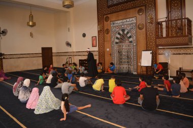 Cairo, Egypt, August 7 2022: A mosque preacher Imam performs a religious Khutbah (sermon) for young Muslim children inside a mosque during the summer Islamic educational program for kids in the mosque