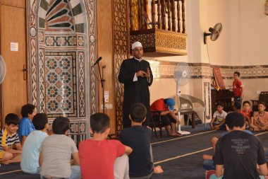 Cairo, Egypt, August 7 2022: A mosque preacher Imam performs a religious Khutbah (sermon) for young Muslim children inside a mosque during the summer Islamic educational program for kids in the mosque