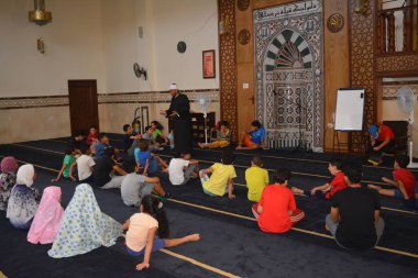 Cairo, Egypt, August 7 2022: A mosque preacher Imam performs a religious Khutbah (sermon) for young Muslim children inside a mosque during the summer Islamic educational program for kids in the mosque