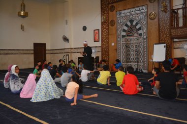 Cairo, Egypt, August 7 2022: A mosque preacher Imam performs a religious Khutbah (sermon) for young Muslim children inside a mosque during the summer Islamic educational program for kids in the mosque