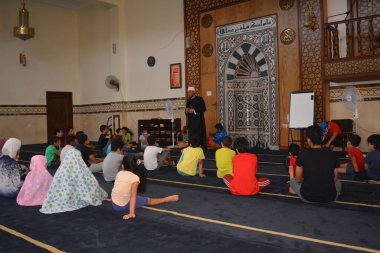Cairo, Egypt, August 7 2022: A mosque preacher Imam performs a religious Khutbah (sermon) for young Muslim children inside a mosque during the summer Islamic educational program for kids in the mosque