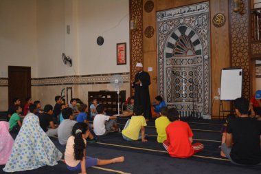 Cairo, Egypt, August 7 2022: A mosque preacher Imam performs a religious Khutbah (sermon) for young Muslim children inside a mosque during the summer Islamic educational program for kids in the mosque