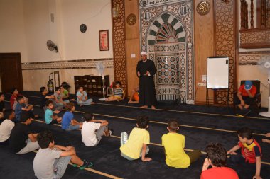 Cairo, Egypt, August 7 2022: A mosque preacher Imam performs a religious Khutbah (sermon) for young Muslim children inside a mosque during the summer Islamic educational program for kids in the mosque