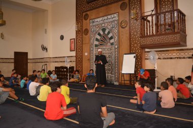 Cairo, Egypt, August 7 2022: A mosque preacher Imam performs a religious Khutbah (sermon) for young Muslim children inside a mosque during the summer Islamic educational program for kids in the mosque