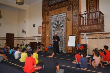 Cairo, Egypt, August 7 2022: A mosque preacher Imam performs a religious Khutbah (sermon) for young Muslim children inside a mosque during the summer Islamic educational program for kids in the mosque