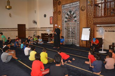 Cairo, Egypt, August 7 2022: A mosque preacher Imam performs a religious Khutbah (sermon) for young Muslim children inside a mosque during the summer Islamic educational program for kids in the mosque