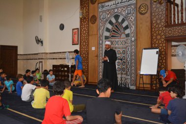 Cairo, Egypt, August 7 2022: A mosque preacher Imam performs a religious Khutbah (sermon) for young Muslim children inside a mosque during the summer Islamic educational program for kids in the mosque
