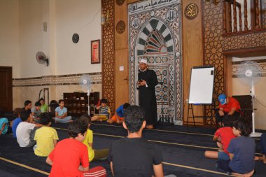 Cairo, Egypt, August 7 2022: A mosque preacher Imam performs a religious Khutbah (sermon) for young Muslim children inside a mosque during the summer Islamic educational program for kids in the mosque