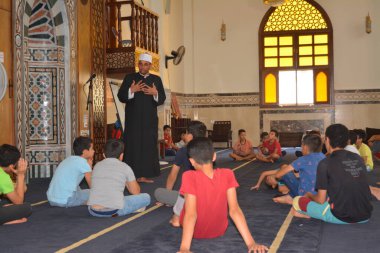 Cairo, Egypt, August 7 2022: A mosque preacher Imam performs a religious Khutbah (sermon) for young Muslim children inside a mosque during the summer Islamic educational program for kids in the mosque