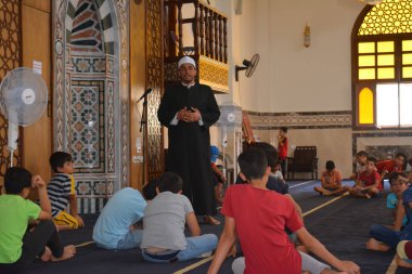 Cairo, Egypt, August 7 2022: A mosque preacher Imam performs a religious Khutbah (sermon) for young Muslim children inside a mosque during the summer Islamic educational program for kids in the mosque