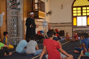 Cairo, Egypt, August 7 2022: A mosque preacher Imam performs a religious Khutbah (sermon) for young Muslim children inside a mosque during the summer Islamic educational program for kids in the mosque