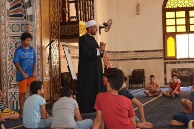 Cairo, Egypt, August 7 2022: A mosque preacher Imam performs a religious Khutbah (sermon) for young Muslim children inside a mosque during the summer Islamic educational program for kids in the mosque