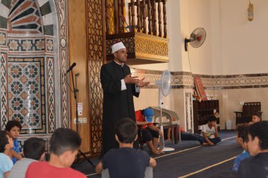 Cairo, Egypt, August 7 2022: A mosque preacher Imam performs a religious Khutbah (sermon) for young Muslim children inside a mosque during the summer Islamic educational program for kids in the mosque