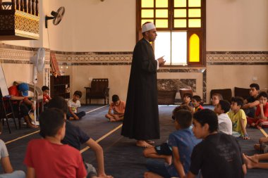 Cairo, Egypt, August 7 2022: A mosque preacher Imam performs a religious Khutbah (sermon) for young Muslim children inside a mosque during the summer Islamic educational program for kids in the mosque