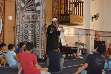Cairo, Egypt, August 7 2022: A mosque preacher Imam performs a religious Khutbah (sermon) for young Muslim children inside a mosque during the summer Islamic educational program for kids in the mosque