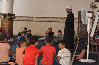 Cairo, Egypt, August 7 2022: A mosque preacher Imam performs a religious Khutbah (sermon) for young Muslim children inside a mosque during the summer Islamic educational program for kids in the mosque