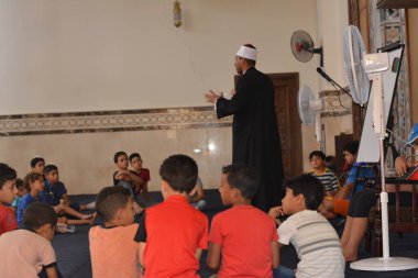 Cairo, Egypt, August 7 2022: A mosque preacher Imam performs a religious Khutbah (sermon) for young Muslim children inside a mosque during the summer Islamic educational program for kids in the mosque
