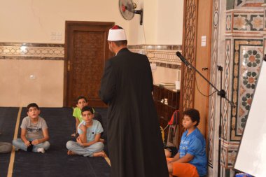 Cairo, Egypt, August 7 2022: A mosque preacher Imam performs a religious Khutbah (sermon) for young Muslim children inside a mosque during the summer Islamic educational program for kids in the mosque