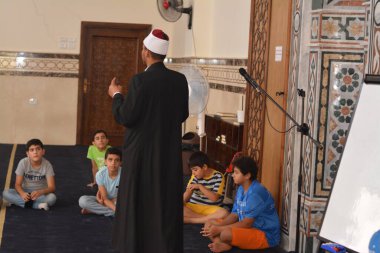 Cairo, Egypt, August 7 2022: A mosque preacher Imam performs a religious Khutbah (sermon) for young Muslim children inside a mosque during the summer Islamic educational program for kids in the mosque