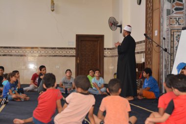 Cairo, Egypt, August 7 2022: A mosque preacher Imam performs a religious Khutbah (sermon) for young Muslim children inside a mosque during the summer Islamic educational program for kids in the mosque