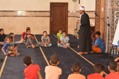 Cairo, Egypt, August 7 2022: A mosque preacher Imam performs a religious Khutbah (sermon) for young Muslim children inside a mosque during the summer Islamic educational program for kids in the mosque