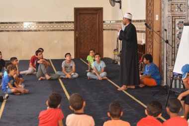 Cairo, Egypt, August 7 2022: A mosque preacher Imam performs a religious Khutbah (sermon) for young Muslim children inside a mosque during the summer Islamic educational program for kids in the mosque