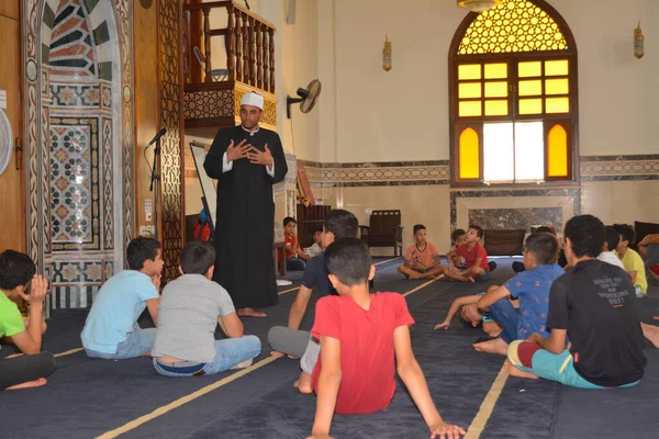 Cairo, Egypt, August 7 2022: A mosque preacher Imam performs a religious Khutbah (sermon) for young Muslim children inside a mosque during the summer Islamic educational program for kids in the mosque