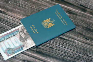 Egyptian passport with 100 EGP LE one hundred Egyptian pounds money banknotes isolated on wooden background, Arab republic of Egypt's passport with the republican golden eagle and Egypt money