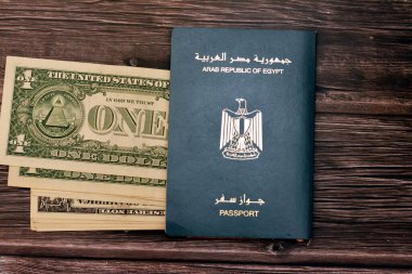 Egyptian passport with American dollars of 1 $ one United states money banknotes isolated on wooden background, Arab republic of Egypt's passport with the republican golden eagle and American money